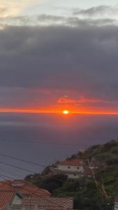 a sunset over the ocean with houses and buildings at Cozy 1 BR w/ balcony, ocean view & perfect sunsets in Ribeira Brava