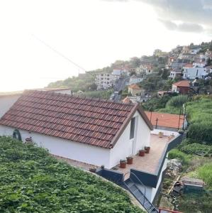 a white house with a red roof on a hill at Cozy 1 BR w/ balcony, ocean view & perfect sunsets in Ribeira Brava