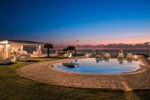 a pool with chairs and tables in a yard at night at Agnanti Suites in Minia