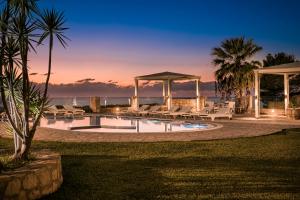 a swimming pool with chairs and a gazebo at Agnanti Suites in Minia