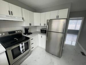 a kitchen with a stainless steel refrigerator and white cabinets at Casa LACK - Tranquila Suites 2 in Ottawa