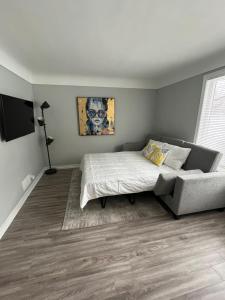 a bedroom with a bed and a couch and a television at Casa LACK - Tranquila Suites 2 in Ottawa