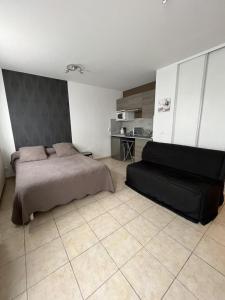 um quarto com uma cama e um sofá preto em Studio Meublé em Bussy-Saint-Georges