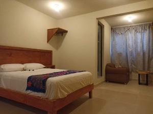 ein Schlafzimmer mit einem Bett, einem Stuhl und einem Fenster in der Unterkunft Suite Villa Real in San Cristóbal de las Casas