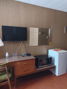 a room with a desk with a microwave and a refrigerator at Sunset Motel in Schreiber