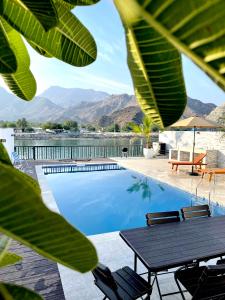 a swimming pool with a table and chairs and mountains at Iconic 4-bedroom villa with pool in Fujairah Palm in Fujairah