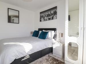 um quarto branco com uma cama com almofadas azuis em Palm View em Newquay