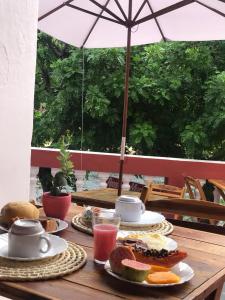 einem Holztisch mit Teller mit Lebensmitteln und einem Regenschirm in der Unterkunft Pousada Maria Bonita - Piranhas, Alagoas. in Piranhas