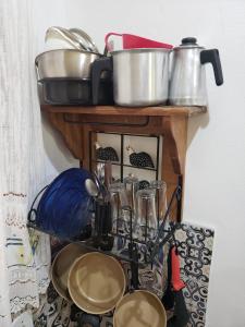 estantería con ollas, sartenes y otros utensilios de cocina en Chalézinho da Montanha - Sítio Pasangas, en Santo Antônio do Pinhal