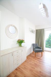 a white living room with a chair and a mirror at Willa Pod Lasem in Jastrzębia Góra