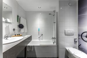 een witte badkamer met een bad en een wastafel bij Velotel Brugge in Brugge