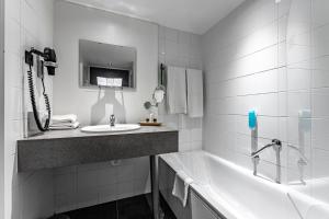 a white bathroom with a sink and a tub at Velotel Brugge in Bruges