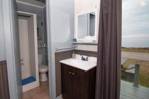 a bathroom with a sink and a toilet and a window at Les Cabines du Phare in Rimouski