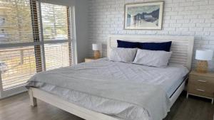 a white bedroom with a large bed with blue pillows at Flinders Lodge unit 9 in Yamba
