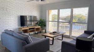 a living room with two blue couches and a tv at Flinders Lodge unit 9 in Yamba