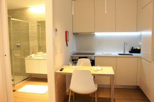 uma cozinha com uma mesa e cadeiras e um lavatório em Oporto Prime Studios no Porto
