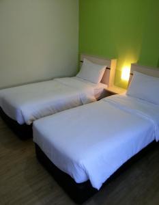 2 camas en una habitación de hotel con sábanas blancas en Merlin Hotel Penang, en George Town