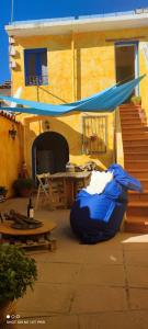 une terrasse avec une tente bleue, une table et une maison dans l'établissement Sa ventana asulla, à San Vito