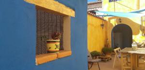 un bâtiment bleu avec une fenêtre et une plante en pot dans l'établissement Sa ventana asulla, à San Vito