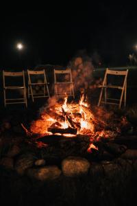 a fire pit with three chairs around it at night at Drwalski Zakątek in Zatory