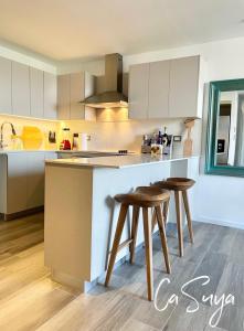 a kitchen with white cabinets and wooden stools at CaSuya Airali apartments with heated pool, gym in city center in Guatemala