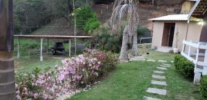 um quintal com uma grelha e flores e uma casa em Casa Grande da Montanha - Sítio Pasangas em Santo Antônio do Pinhal