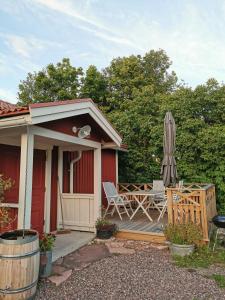 a house with a deck with a table and an umbrella at Idyllisk nybyggd stuga på Sollerön. in Sollerön
