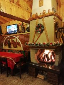 a room with a fireplace with a table and a television at Kovacha Guest House in Raduil