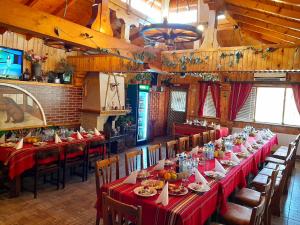 uma mesa longa num restaurante com mesas e cadeiras vermelhas em Kovacha Guest House em Raduil