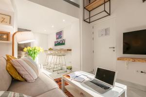 a living room with a couch and a laptop on a table at Loft duplex Sevilla wall in Seville