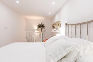 a white bedroom with a bed with white sheets at Loft duplex Sevilla wall in Seville
