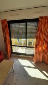 um quarto com uma grande janela com uma mesa e cadeiras em Studio Climatisé Résidence Odalys Saint Loup,piscine ,parking privé et superette em Cap d'Agde