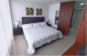 1 dormitorio con 1 cama grande con sábanas blancas en Apartasuites AAA Modelia Bogotá, en Bogotá