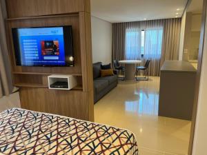 uma sala de estar com um sofá e uma televisão de ecrã plano em LANDMARK By Hotelaria Brasil em São Paulo