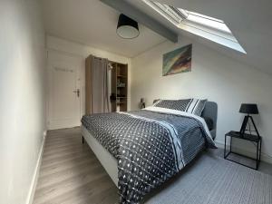 een slaapkamer met een bed met een zwart-wit dekbed bij Centre-ville f3 tout confort in Beaumont-sur-Oise