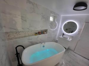 a white bathroom with a tub and a sink at Gite des Rêves 