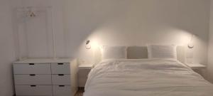 a white bedroom with a white bed and a nightstand at Gite des Rêves 