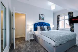 a bedroom with a large bed and a blue headboard at Westwood Lodge Serviced Apartment in Coventry