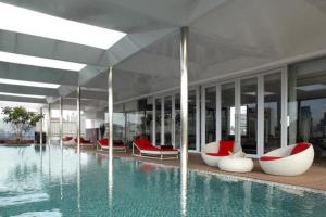 a building with a pool with red and white chairs at Morrissey Hotel in Jakarta
