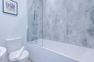 une salle de bain blanche avec douche et toilettes dans l'établissement Beechwood Lodge Serviced Apartment, à Coventry 18 autres photos