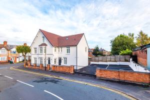 una casa blanca con techo marrón en una calle en Beechwood Lodge Serviced Apartment, en Coventry