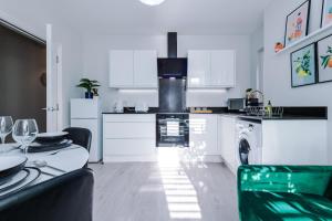 a kitchen with white cabinets and a table and a stove at Beechwood Lodge Serviced Apartment in Coventry