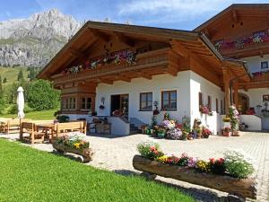 a house in the mountains with flowers in front at Gästehaus Gschwandtner in Mühlbach am Hochkönig