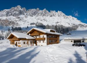 a house in the snow with a mountain in the background at Gästehaus Gschwandtner in Mühlbach am Hochkönig