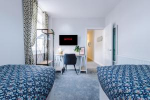 1 dormitorio con 2 camas y escritorio con monitor en Hearsall Place Serviced Apartment en Coventry