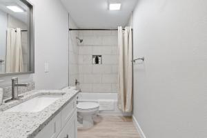 ein weißes Bad mit einem WC und einem Waschbecken in der Unterkunft Evonify Stays - Highland - Stylish Furnished Apartments in Austin
