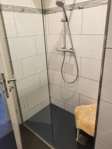 a shower with a glass door and a stool at Ferienwohnung Markranstädt in Markranstädt