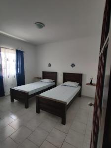 two beds sitting in a room with a tiled floor at Apartamento Coral in Santa Maria