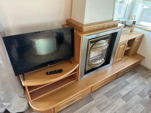 a television sitting on a wooden entertainment center at Willerby Granada 2-Bedroom Parkhome, Glasgow in Uddingston