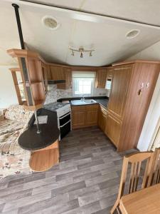 a small kitchen with wooden cabinets and a table at Willerby Granada 2-Bedroom Parkhome, Glasgow in Uddingston